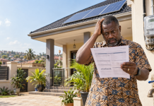 THE ONLY THING THAT FLOWS REGULARLY IS THE BILL ECG estimated billing in Ghana illustrated by a homeowner holding a high electricity bill beside rooftop solar panels